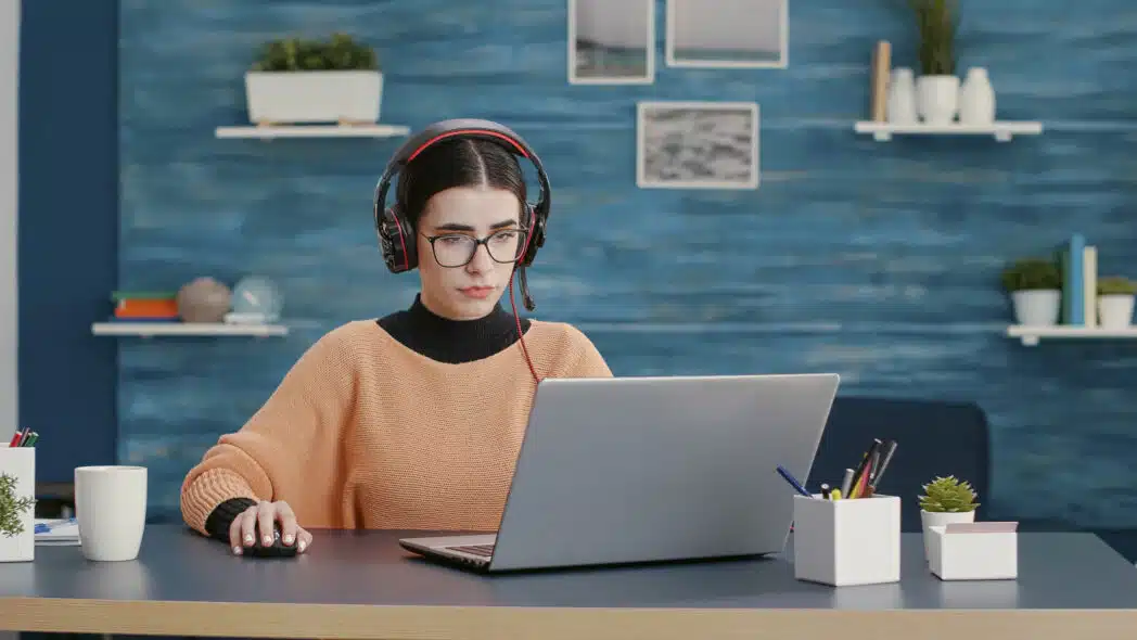 University student using headphones and laptop to attend online class University student using headphones and laptop to attend online class